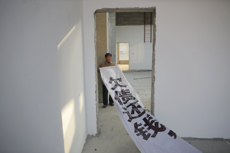 A migrant worker shows a banner inside a building that is under construction as a part of the Zixia Garden development complex in Qianan. Photo: Damir Sagolj, Reuters.