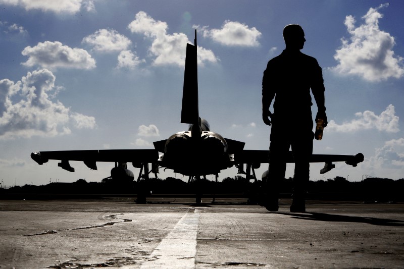 A British soldier walks by a Royal Air Force Typhoon aircraft before it takes off from RAF Akrotiri in Cyprus for a mission in Iraq