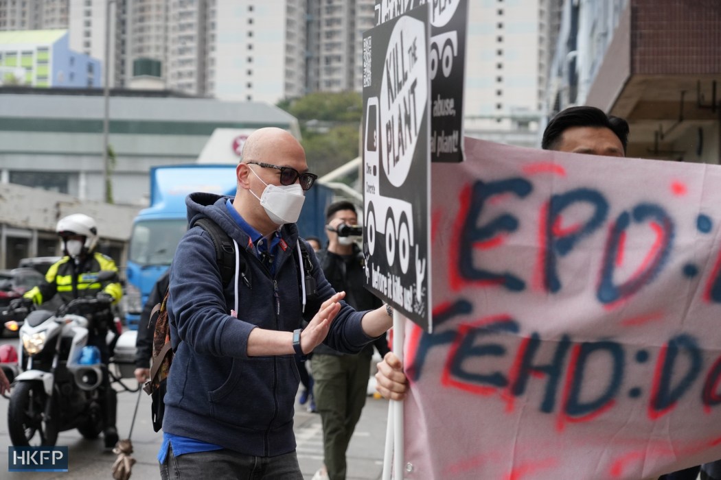 A plain clothes police offer telling protesters to stay on the sidewalk on February 4, 2023. Photo: Candice Chau/HKFP. 