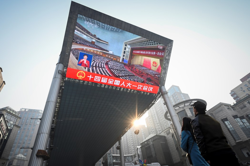 People watch live coverage of the opening session of the National Peoples Congress (NPC) on an outdoor screen in Beijing on March 5, 2023. Photo: Wang Zhao/AFP.