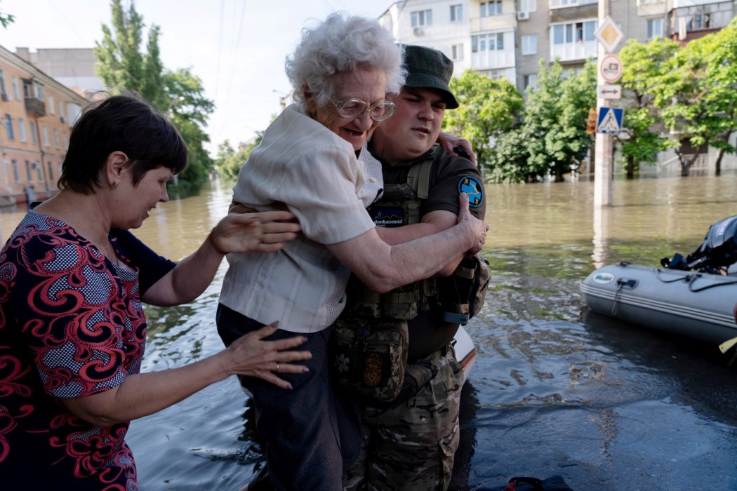 A Ukrainian serviceman helps local residents during an evacuation from a flooded area in Kherson on June 7, 2023, following damage sustained at Kakhovka hydroelectric power plant dam. Photo: Aleksey Filippov/AFP.