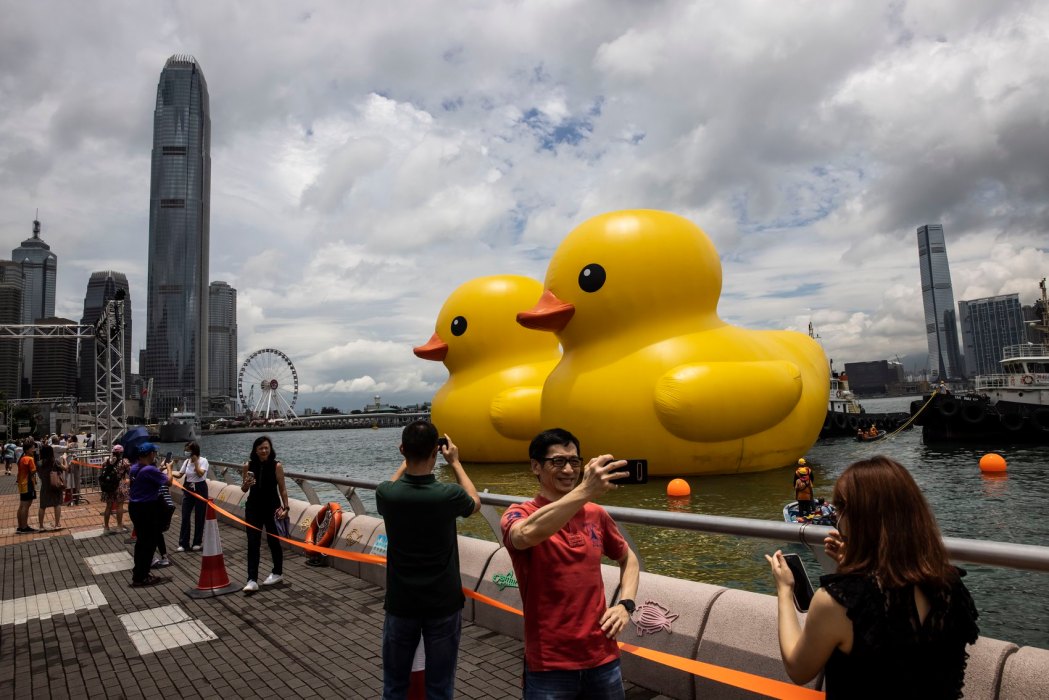 People take photos of two large inflatable yellow ducks called "Double Duck" by Dutch artist Florentijn Hofman in Victoria Harbour in Hong Kong on June 9, 2023. Photo: Isaac Lawrence/AFP.