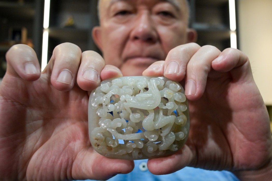 Chang Juben, chairman of Taiwan's Association of Jade Collectors, displaying a Yuan dynasty (1217-1368) jade belt ornament showing a carving of a dragon among clouds, in Taipei on July 19, 2023. Photo: Sam Yeh/AFP.