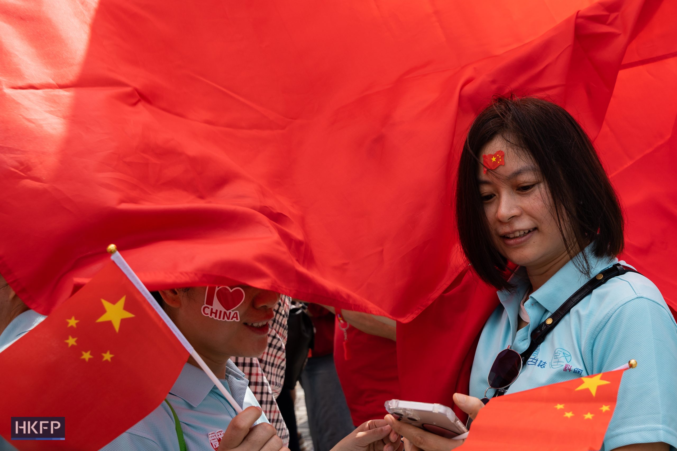People hold red flags to celebrate the national day in Tsim Sha Tsui, Hong Kong, on October 1, 2023. Photo: Kyle Lam/HKFP.