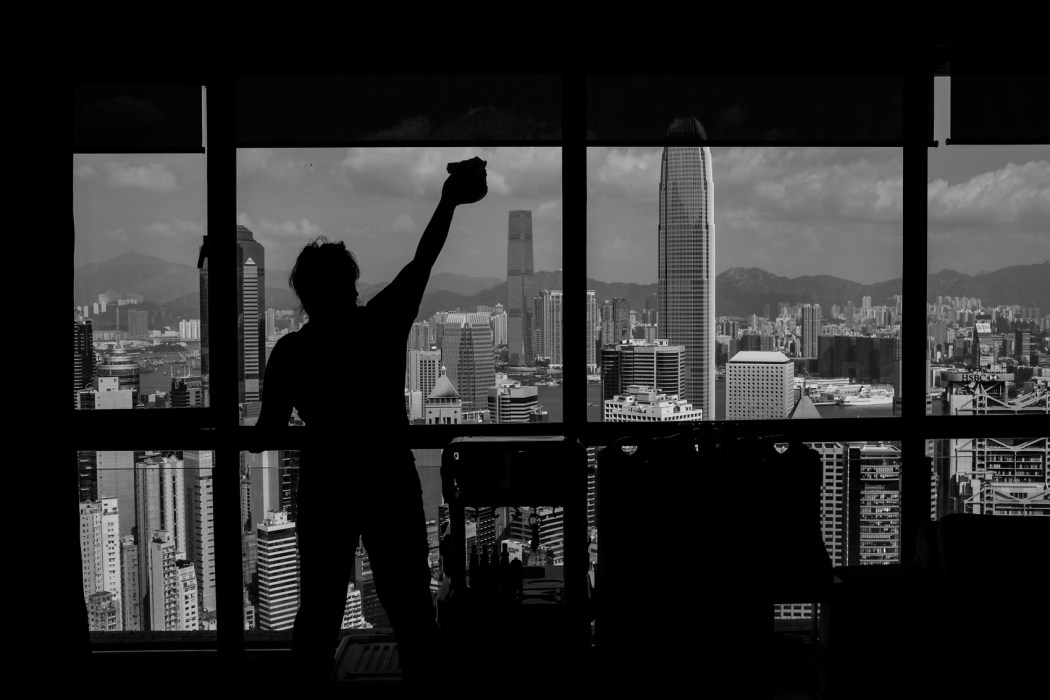 A migrant worker in Hong Kong cleans the window of her employer's home. Photo: Xyza Cruz Bacani.
