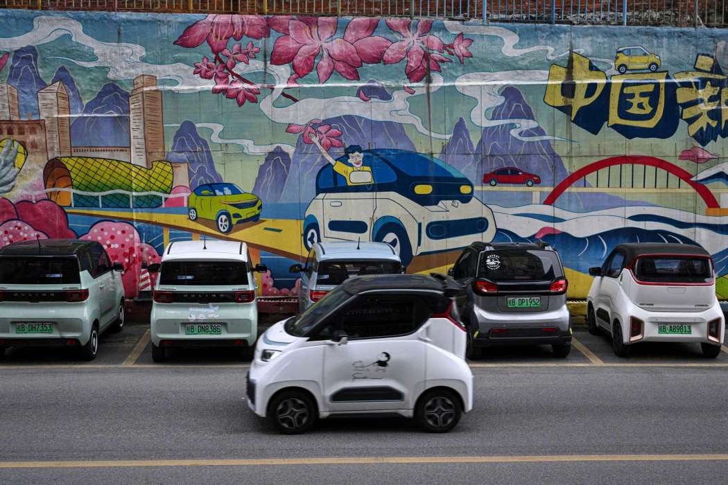 A mini electric vehicle drives past a mural with electric cars on a street in Liuzhou, in southern China's Guangxi province on January 24, 2024. Photo: Jade Gao/AFP.