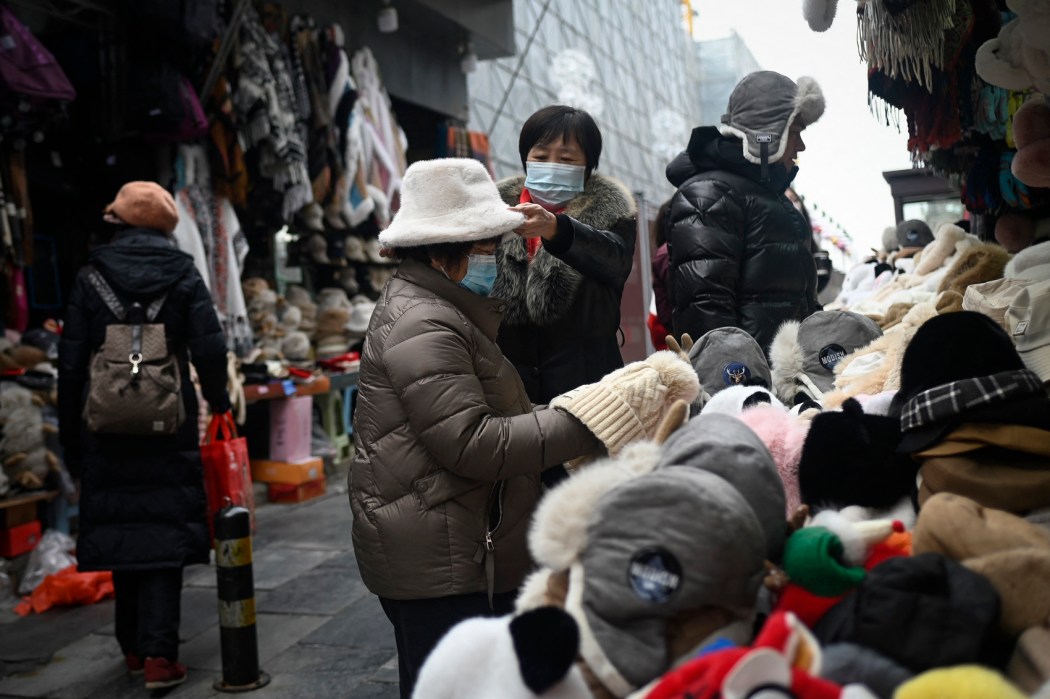 People check caps at a street stall in Beijing on February 28, 2024. 