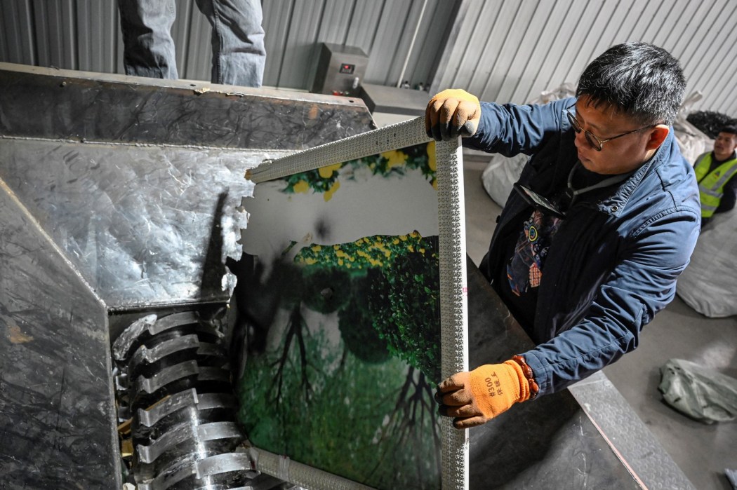 Worker Yang Weiguang places a large wedding photo into a shredding machine at a warehouse in Langfang, in northern China's Hebei province on March 27, 2024.