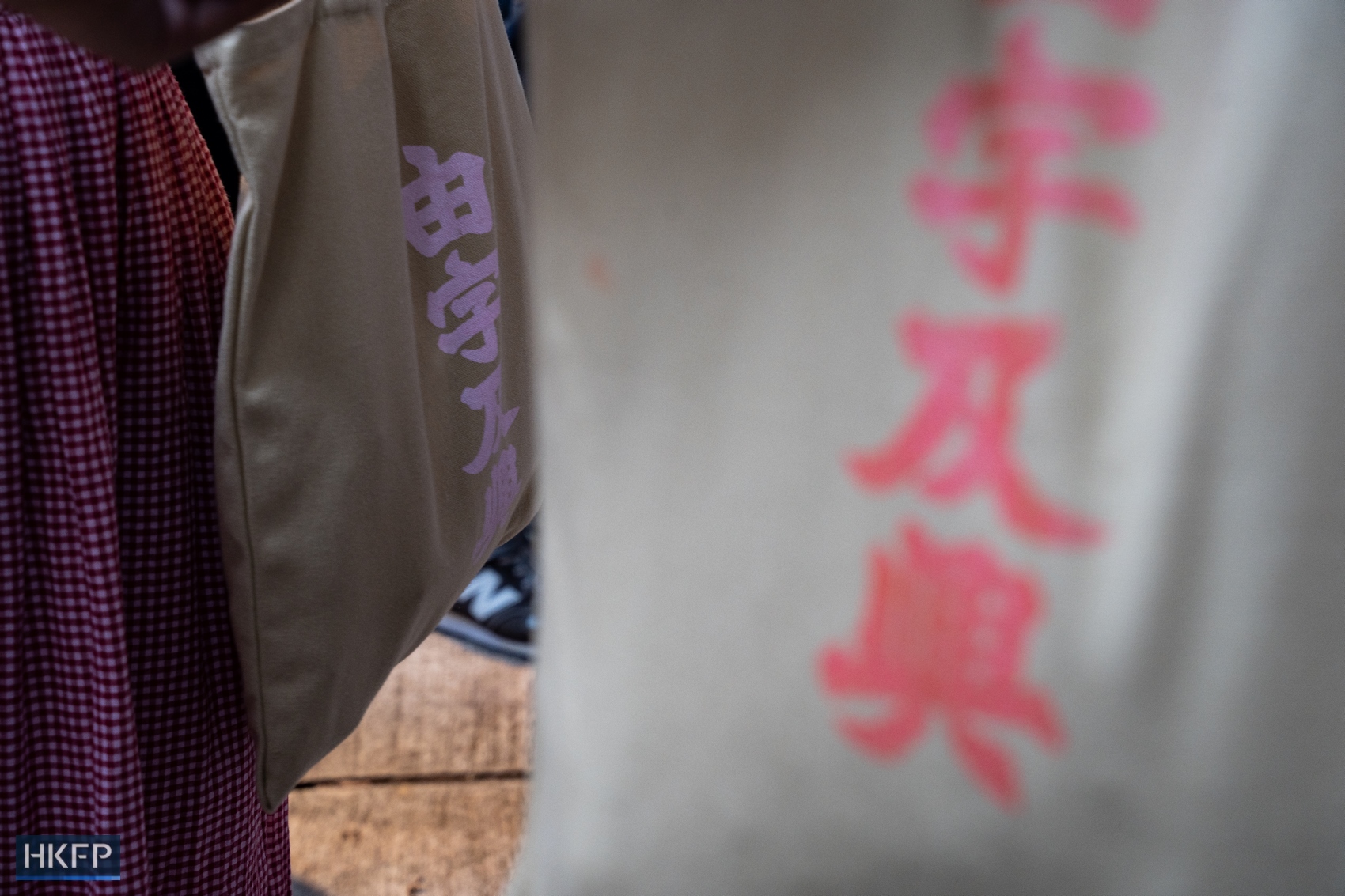 Readers carry a canvas tote bag showcasing the Chinese phrase "From words to prosperity" - an apparent parody of the government's narrative "From stability to prosperity" - on March, 31, 2024. Photo: Kyle Lam/HKFP.