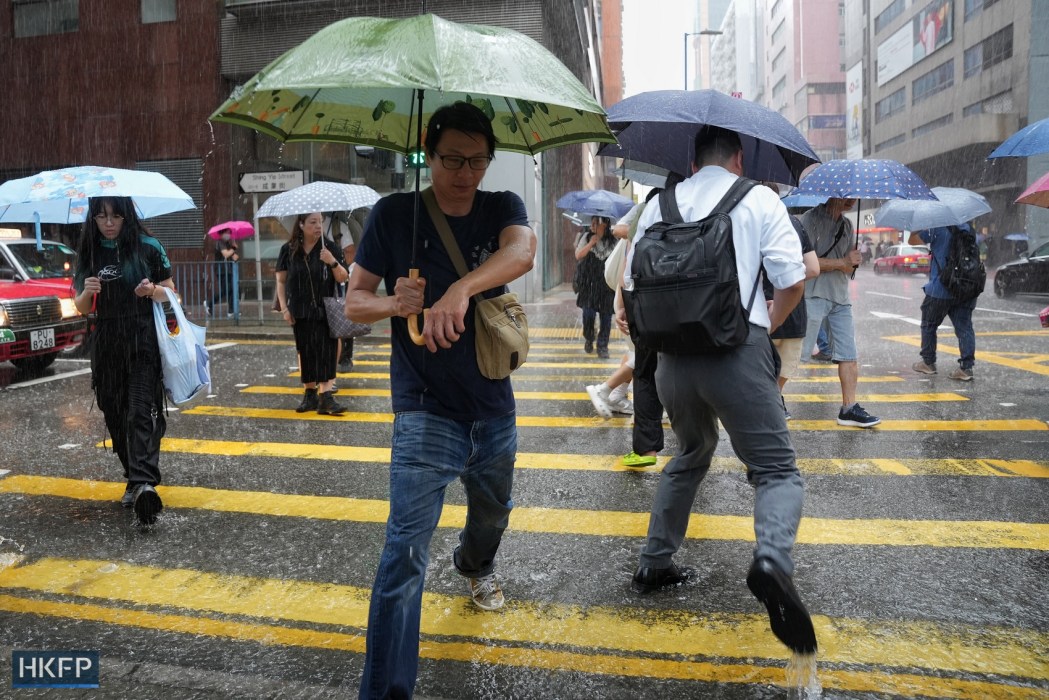 People cross a road in heavy rain in Hong Kong, on May 21, 2024. Photo: Kyle Lam/HKFP. 
