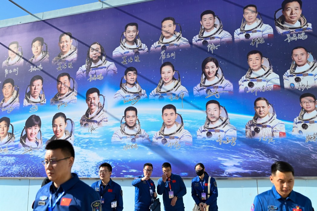 People stand in front of a poster showing astronauts at the Jiuquan Satellite Launch Centre in China's northwestern Gansu province on October 25, 2023, ahead of a mission to the Tiangong space station. Photo: Pedro Pardo/AFP.