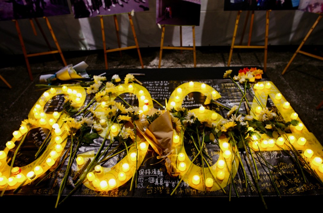 Flowers and candles are seen on a banner during a rally to mark the 35th anniversary of the 1989 Tiananmen Square crackdown, at Liberty Square in Taipei on June 4, 2024. (Photo by Sam Yeh / AFP)